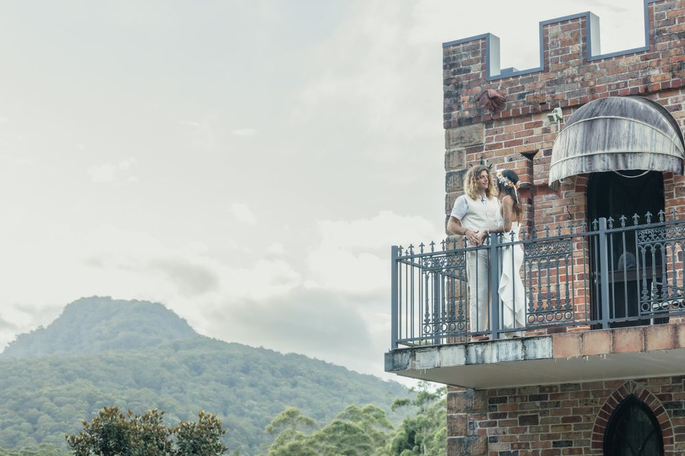 Stone castle balcony with mountain views in misty weather.