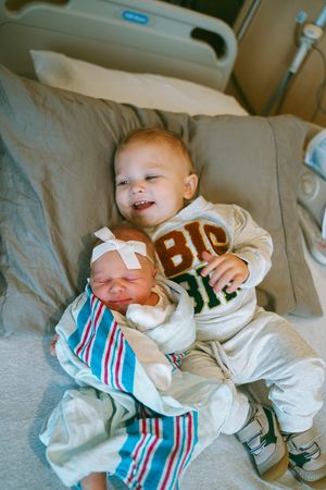 Baby wearing striped outfit lies on hospital bed showing various expressions.