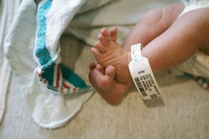 Close-up details of medical bands and tags on a newborn in hospital.