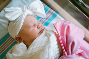 Newborn sleeping peacefully in hospital blankets with medical identification.