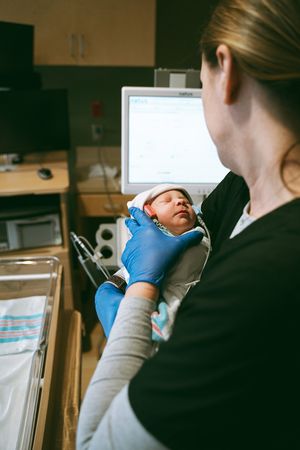 Medical professional examining newborn baby in hospital setting.