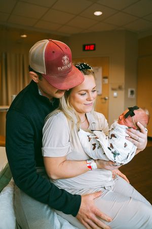 Family shares intimate moments with newborn baby in hospital room.