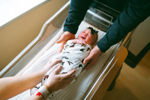 Newborn baby being weighed and measured on a medical scale.