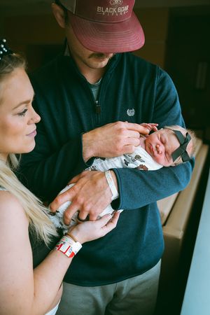 A tender moment with a newborn baby being held while wearing a striped onesie.