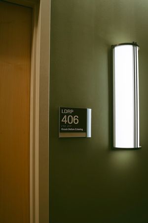 Hospital corridor wall with room 406 sign and modern lighting fixture.