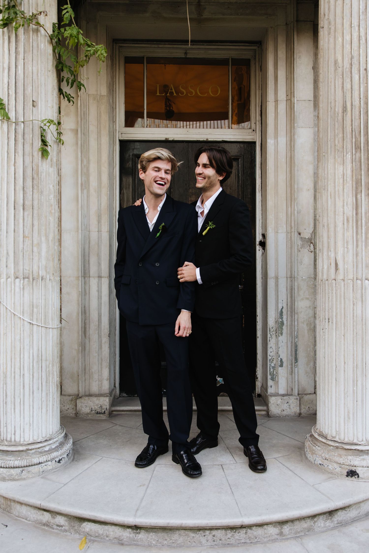 Two people share a joyful moment between classical columns at an entrance.