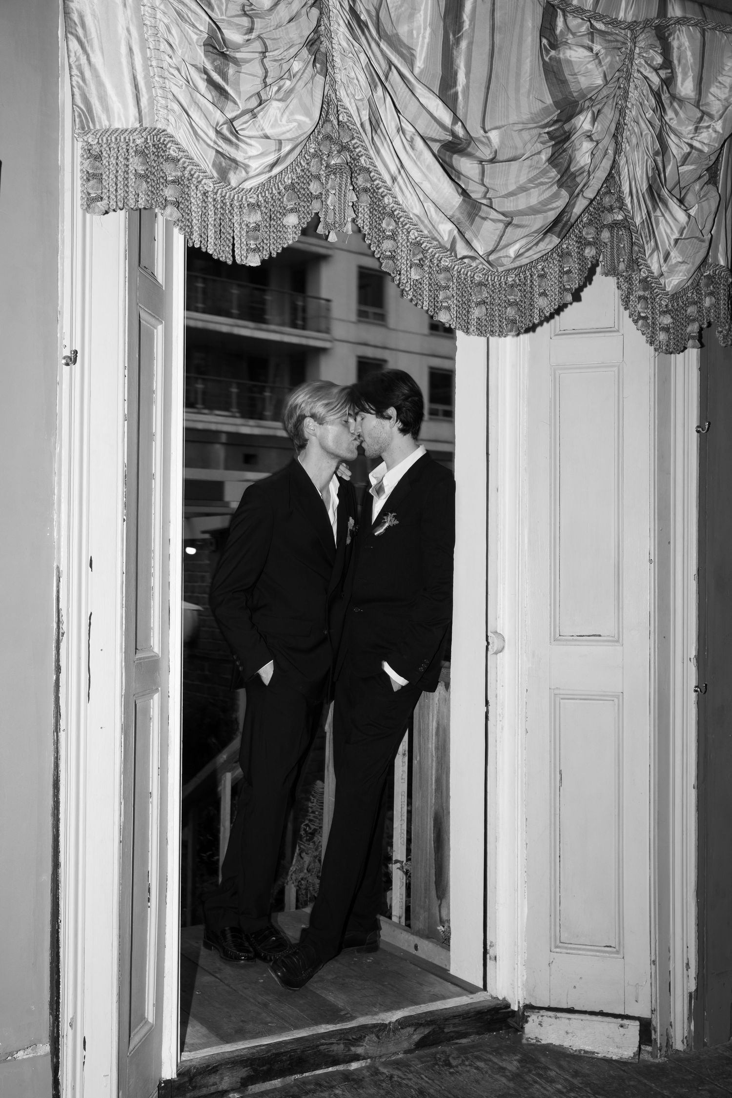 Black and white photograph of intimate moment between two people in formal wear.