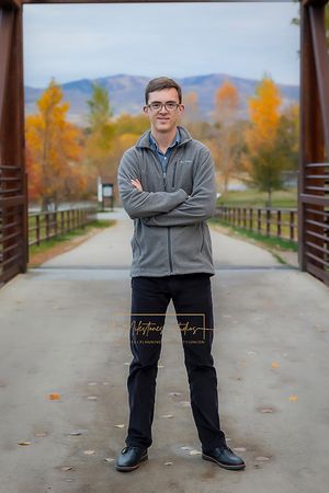 Boise Senior photos Boise white water park Boy standing on bridge with autumn trees in the background