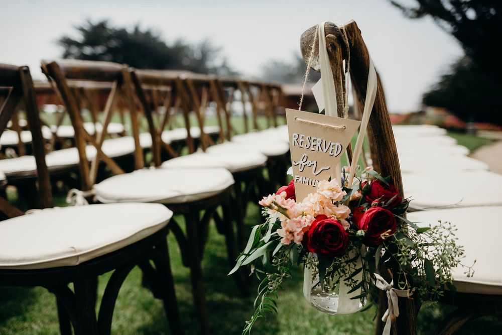 Wedding reception tables set outdoors with rustic wooden chairs and delicate floral centerpieces.