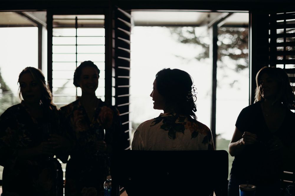Silhouettes of people standing against bright windows in a dark interior space.