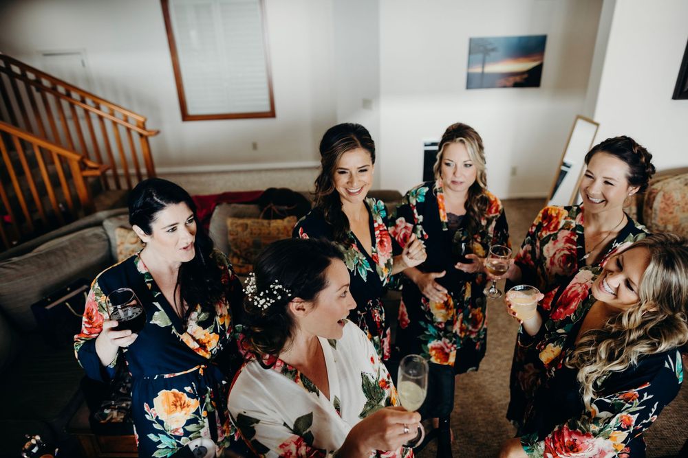 Wedding party getting hair and makeup done while sitting together in preparation for the ceremony.
