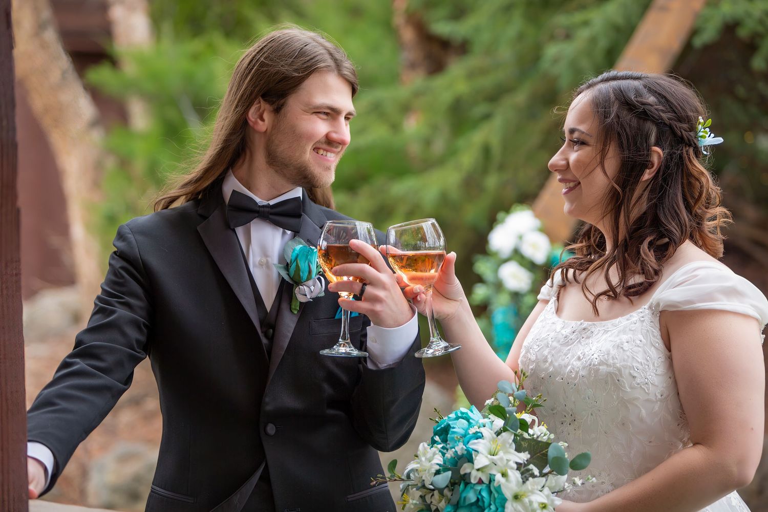 Bride and Groom clinking wine glasses while smiling at each other