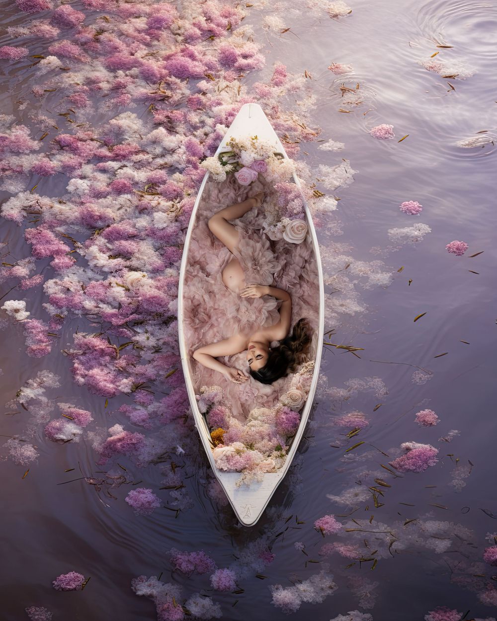 A weathered wooden boat drifts among scattered pink lotus petals on dark rippling water.