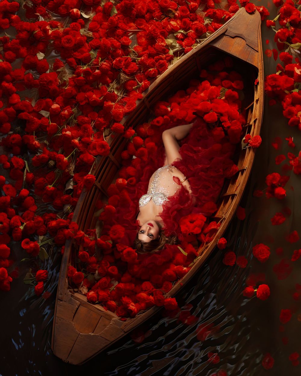 A dramatic composite image shows a sleeping figure surrounded by vibrant red roses against a dark background.