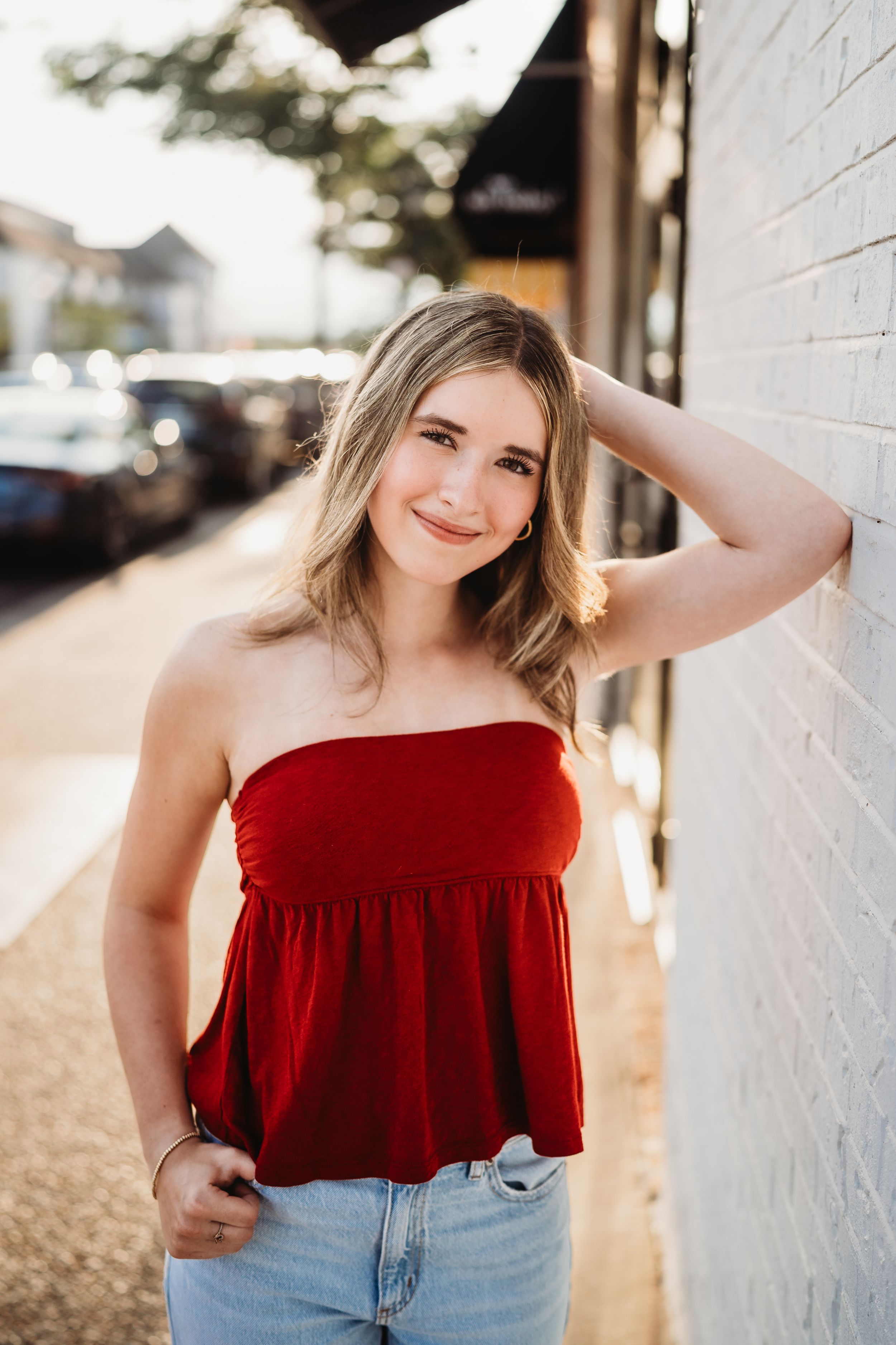 A series of outdoor portrait photos featuring a person in a red strapless top and jeans against a white wall in sunlight.