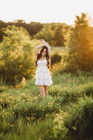 A person in a floral dress twirls joyfully in a sunlit meadow filled with wildflowers during golden hour.