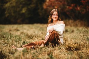 A person lies in a field of golden grass during autumn with warm sunlight creating a dreamy outdoor portrait.