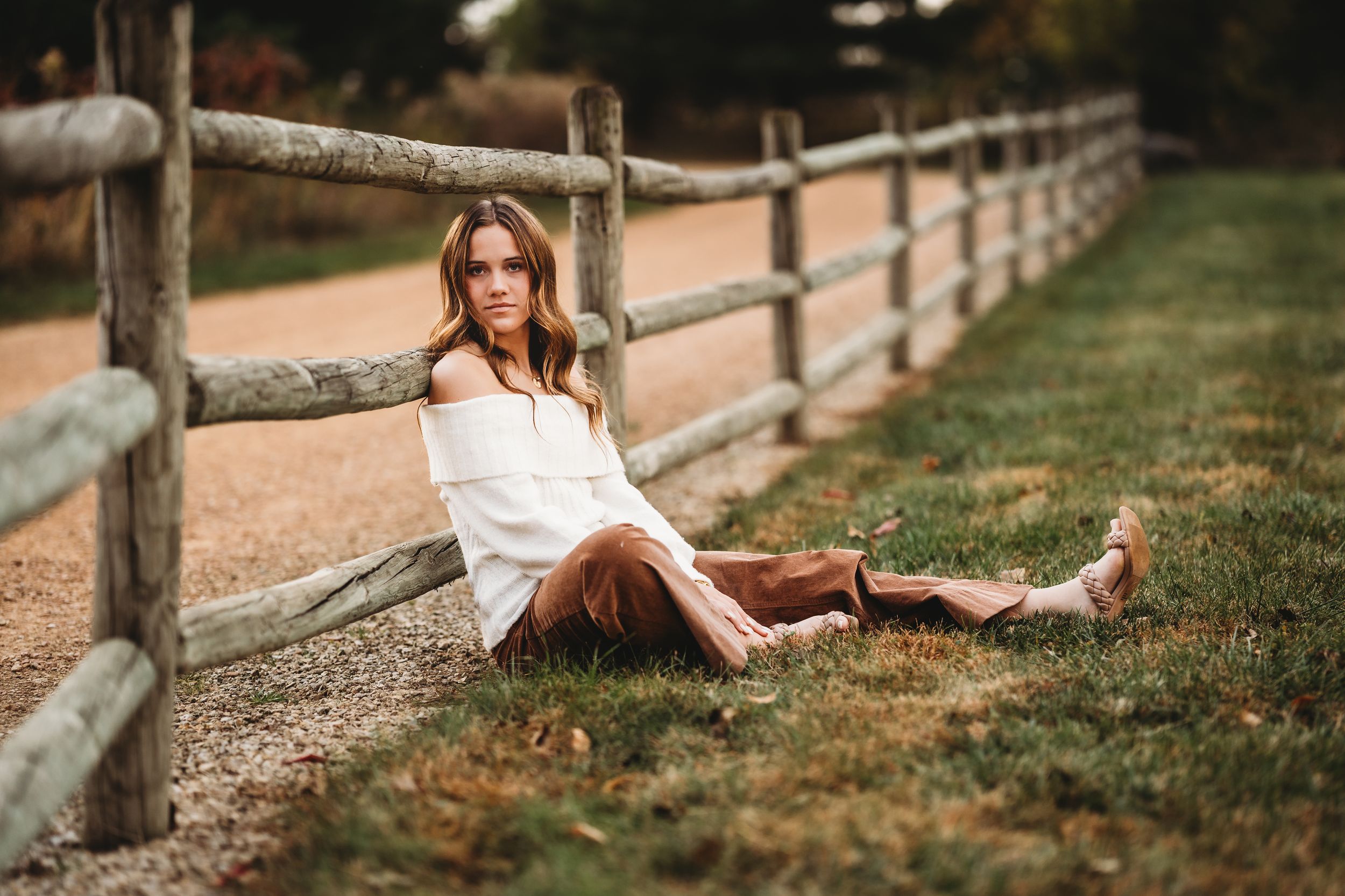 A rustic wooden fence lines a path through autumn grass at sunset creating a peaceful country scene.