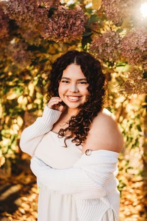 A fall portrait in warm golden light with dried hydrangea flowers in the background and a white sweater.