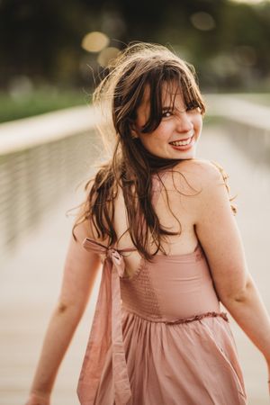 A carefree moment captured in soft lighting as someone in a pink dress moves with windswept hair.
