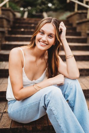 A series of candid portraits showing someone in a white tank top and light jeans lounging on wooden steps outdoors.