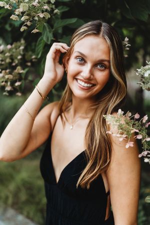 A series of outdoor portrait photos showing someone in a black tank top posing among white flowering branches.