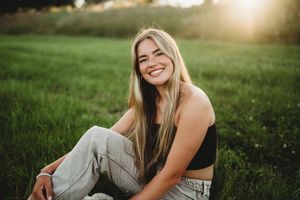 A joyful portrait in a sunlit meadow with green grass and golden evening light.
