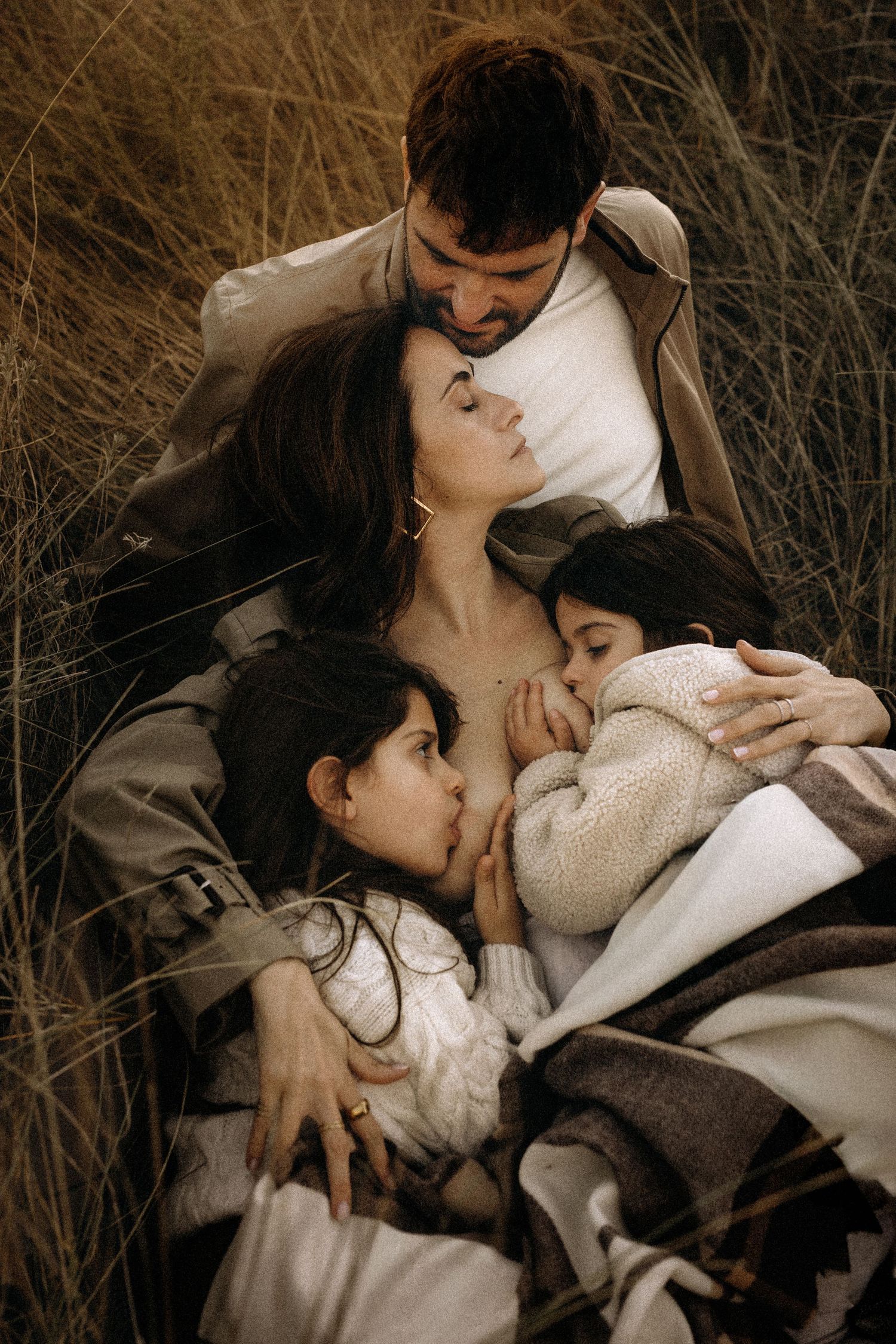 A couple shares an intimate moment lying together on a blanket in a field of dried grass and autumn foliage. Javea photographer
