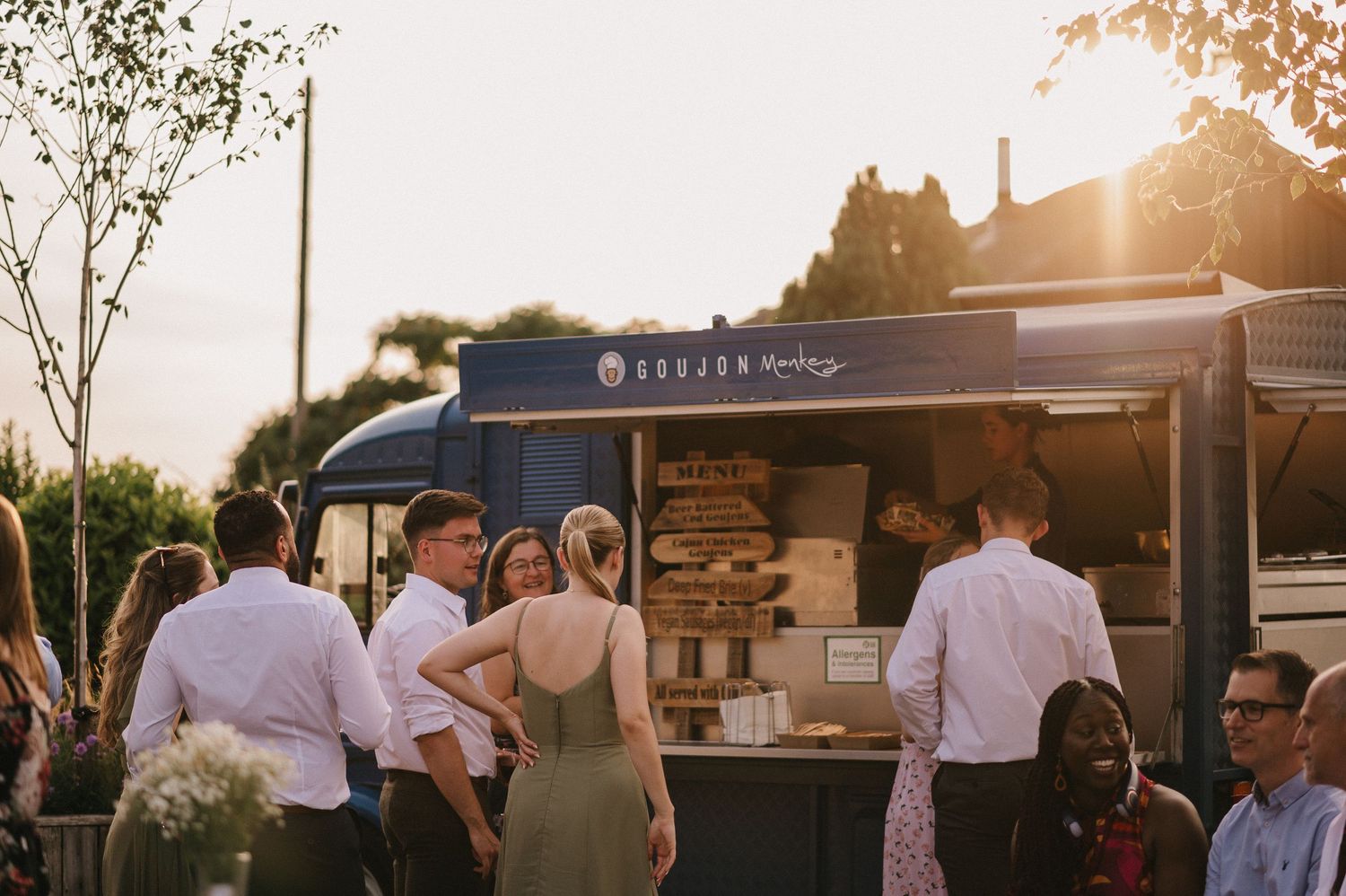 Customers line up at a food truck during sunset at an outdoor event.