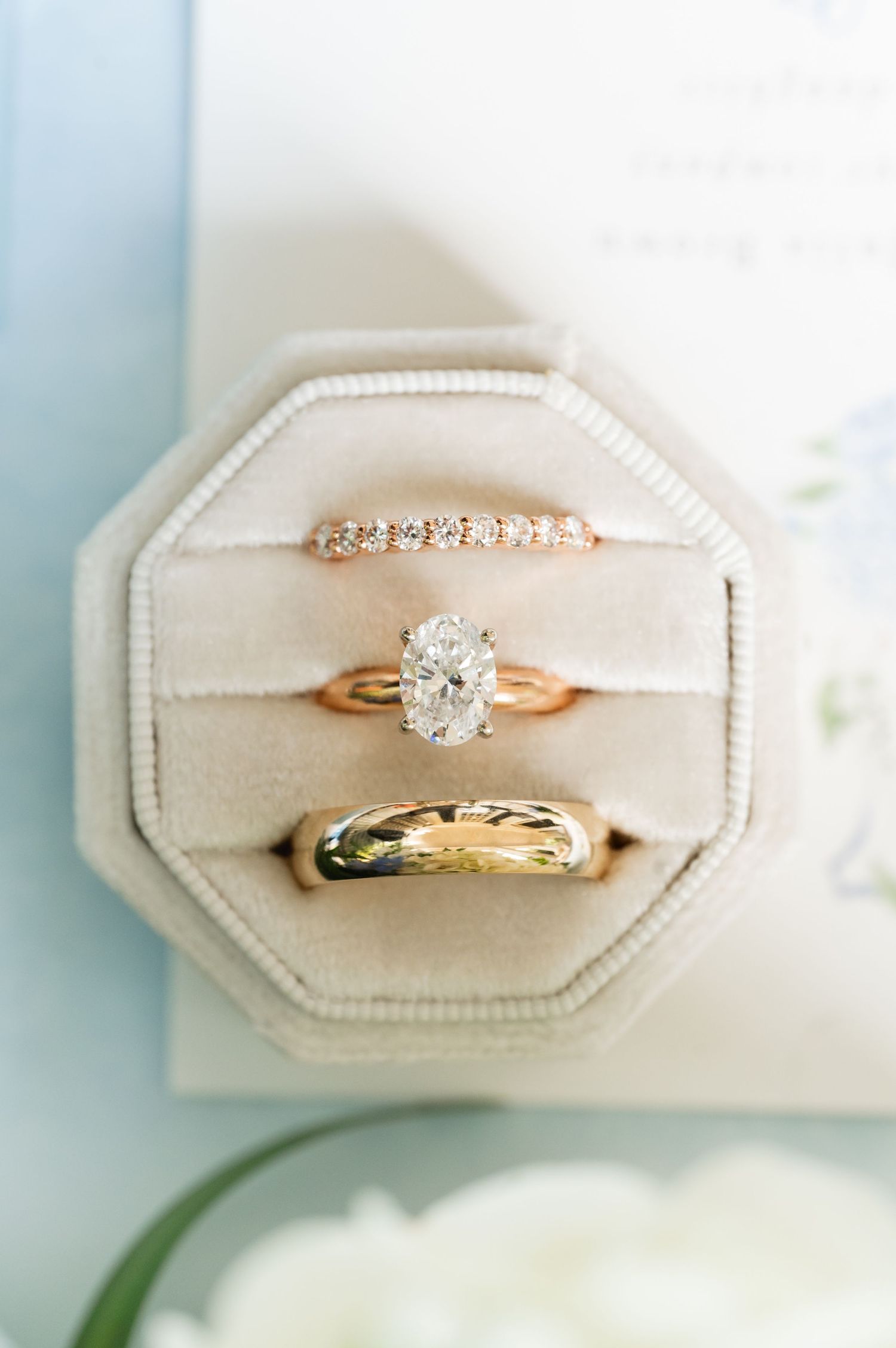Three wedding rings nestled in a cream-colored octagonal ring box.