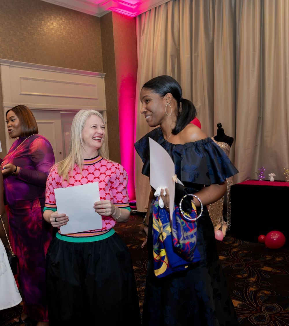 Candid moment of attendees sharing laughter while reviewing papers at social gathering.