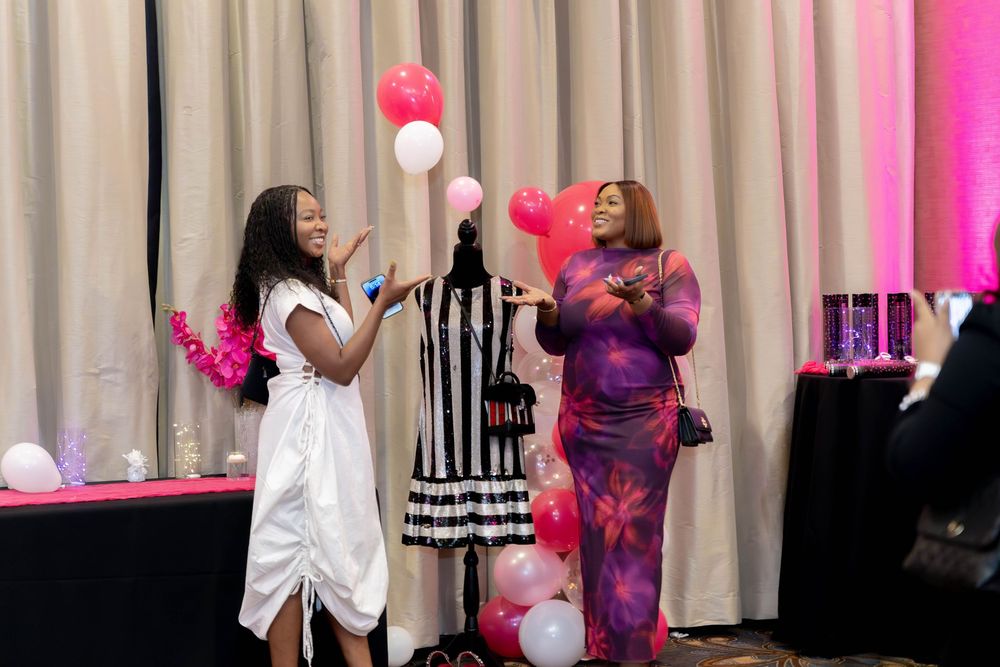 Attendees enjoying a festive celebration with pink and white balloons in an event space.