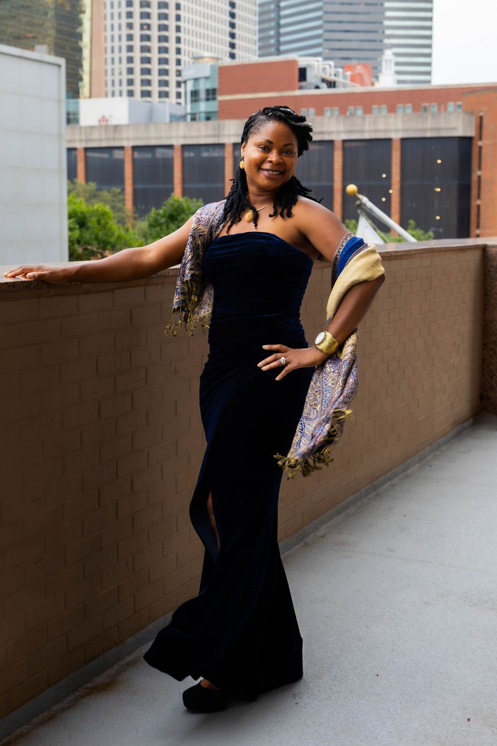 Stylish evening portrait on urban terrace with navy gown and patterned wrap.