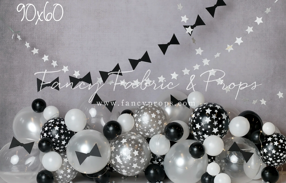 Black and white balloon arch with bows and stars creates an elegant party decoration display.
