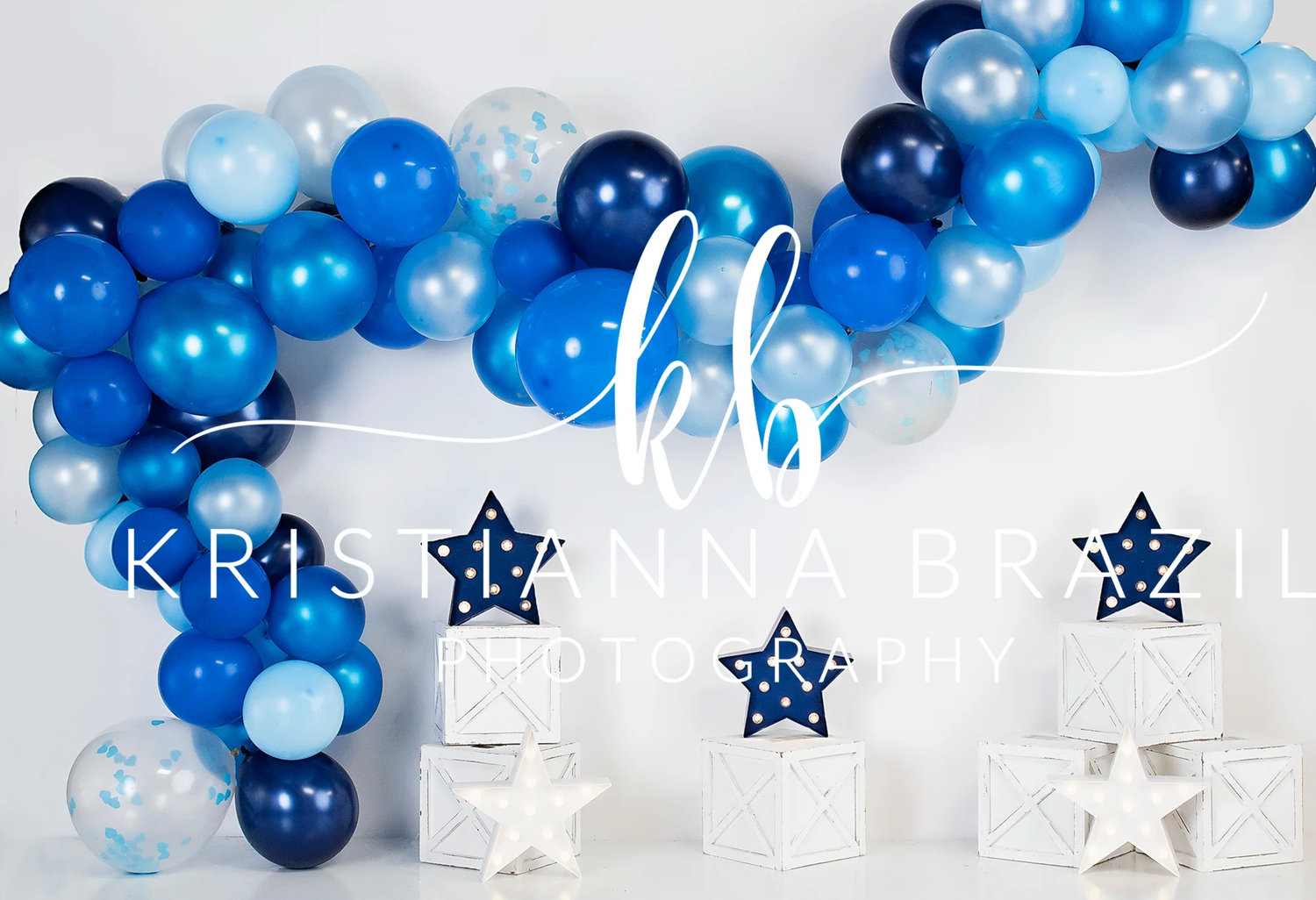 A festive balloon arch in shades of blue and white with star decorations creates an elegant party backdrop.