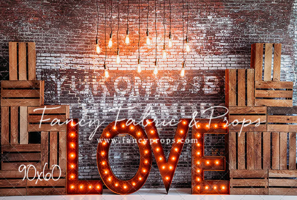 Illuminated LOVE marquee letters against rustic brick wall with wooden decor elements creating romantic ambiance.