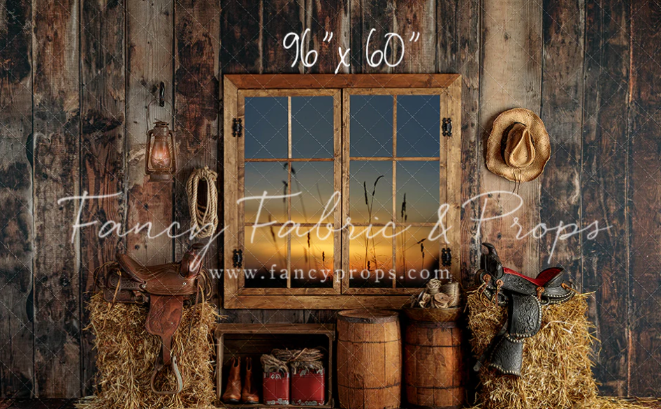 Rustic wooden barn interior with vintage barrels, lanterns, and hay bales illuminated by warm evening light.