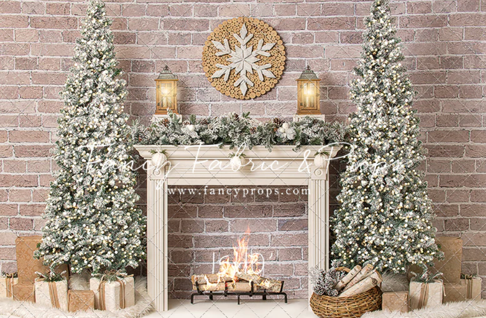 Elegant Christmas mantel display with frosted trees, white stockings, and brick wall backdrop illuminated by warm lighting.