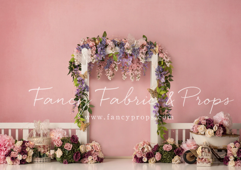 Pink studio backdrop with floral decorations and props arranged for professional photography sessions.