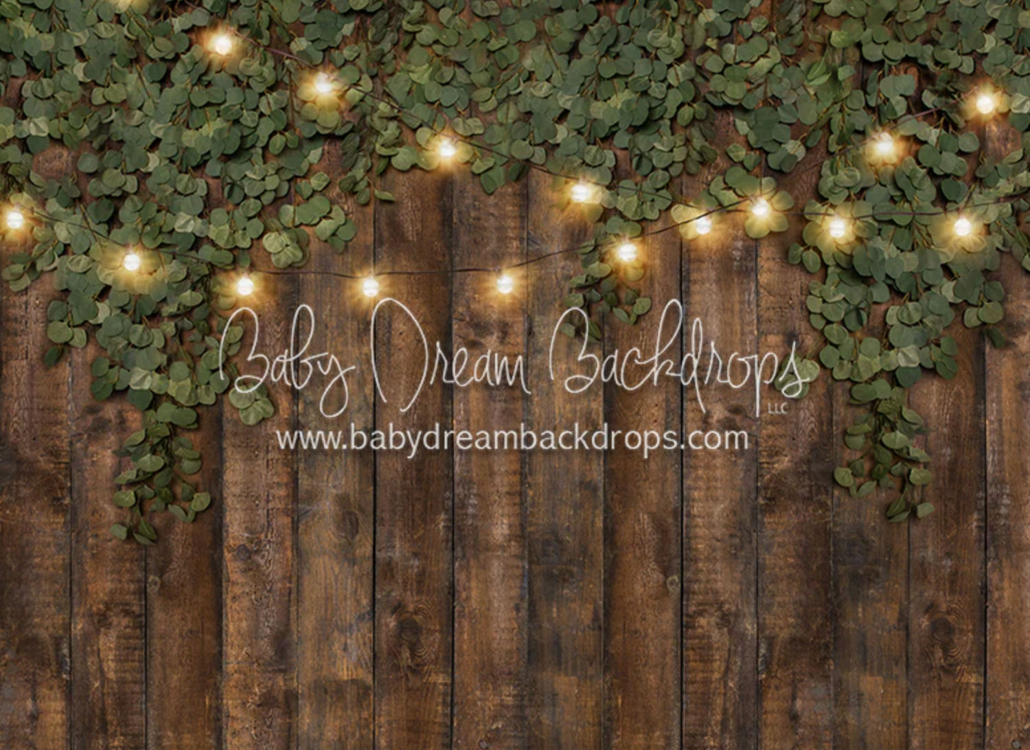 A rustic wooden fence backdrop with glowing string lights and green foliage decorations along the top.