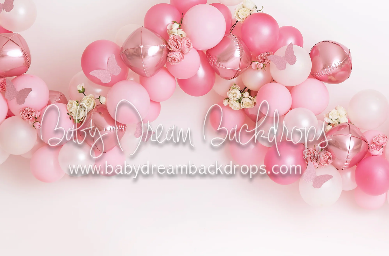 Pink balloon garland with pearl accents decorates a white backdrop for a festive party setting.