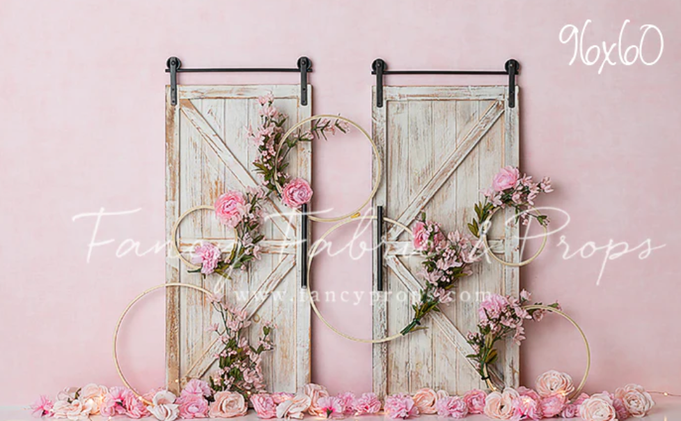 White wooden chairs and floral arrangements create an elegant wedding ceremony setup against a pink backdrop.