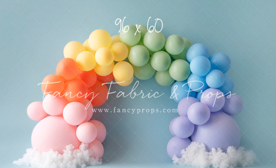 Pastel colored balloon arch with clouds made of cotton batting creates a whimsical rainbow display.