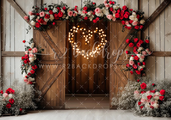 Rustic barn door decorated with floral arch and illuminated heart-shaped lights creates romantic wedding backdrop.