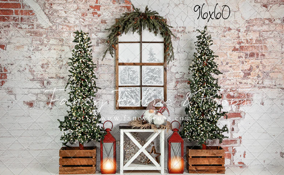 Rustic white brick wall backdrop with window, greenery, and lanterns creates a cozy farmhouse-style photo setting.