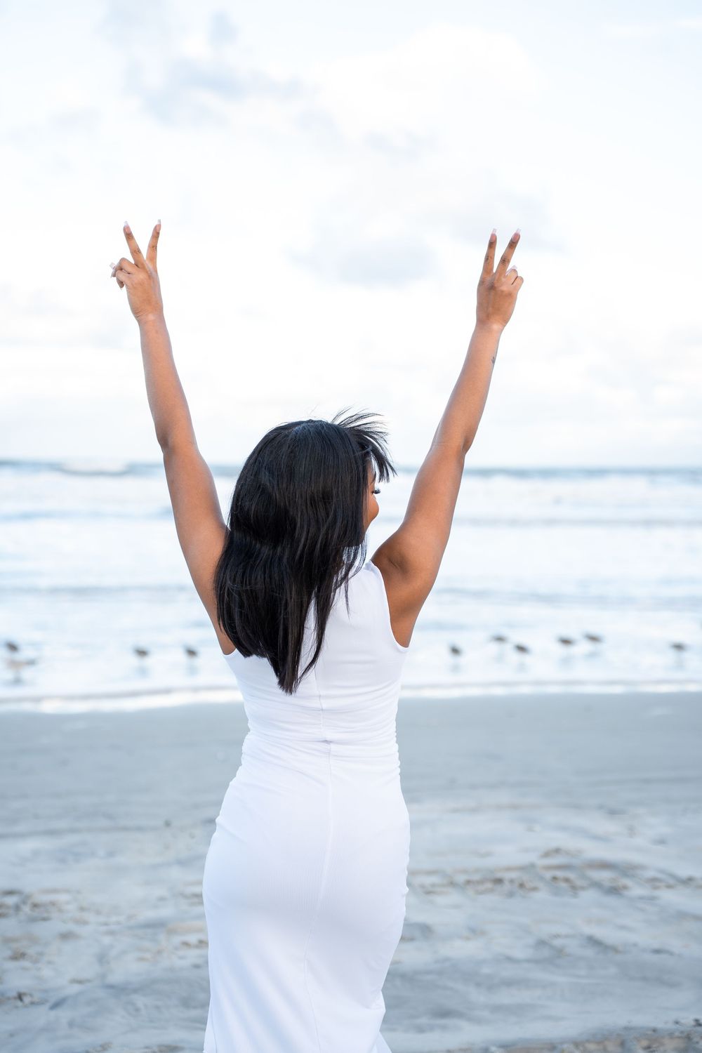 A series of photos showing a person in white clothing celebrating with raised arms on a beach at sunset in Daytona Beach, Florida