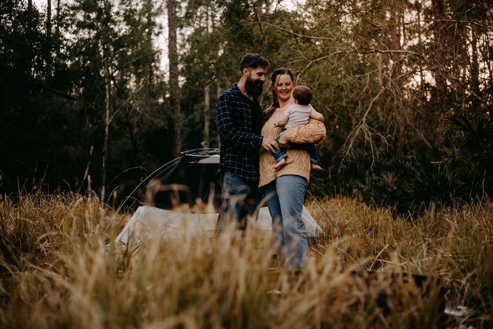Family enjoying tender moments together in a natural outdoor setting during golden hour.