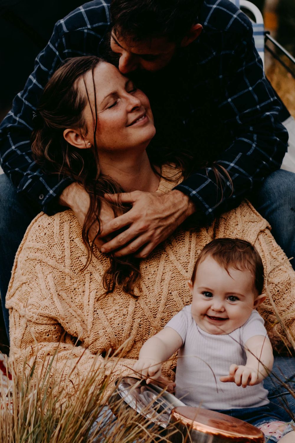 A series of intimate family portraits showing tender moments between parent and baby in warm lighting and cozy knit sweaters.