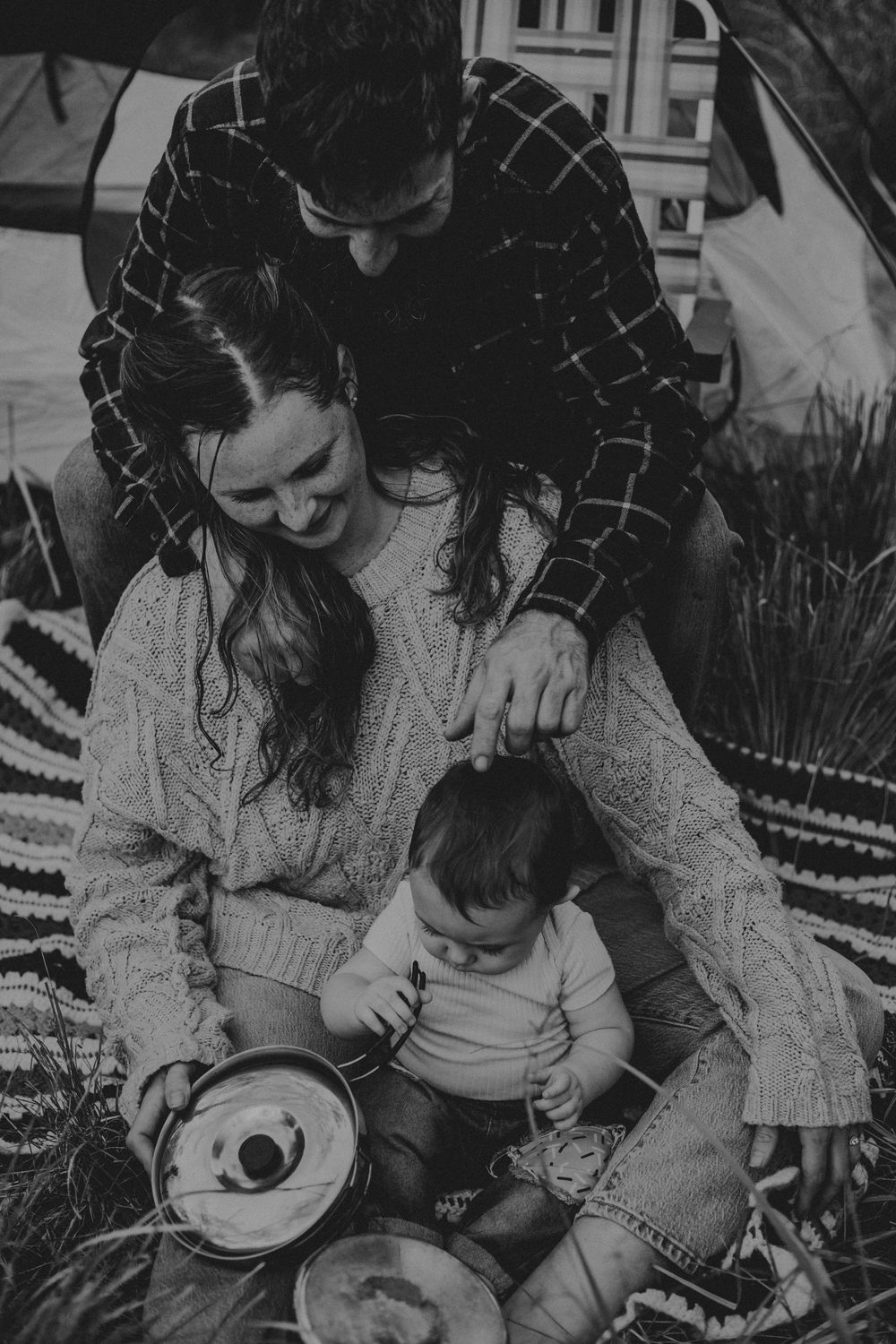 A tender family moment outdoors sharing music and laughter together on a blanket.
