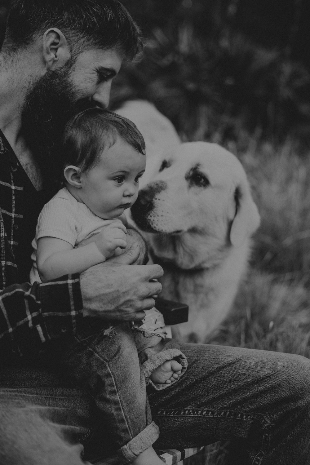 Young child and fluffy white dog sharing a sweet moment together in black and white photography.